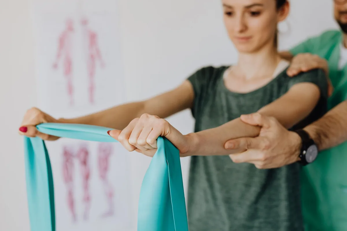 Fisioterapeuta orienta uma paciente em exercício de ombro com faixa elástica